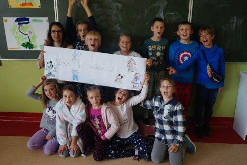 Dzieci z klasy IIIb ubrane w piżamy z panią katechetką na tle tablicy szkolnej
