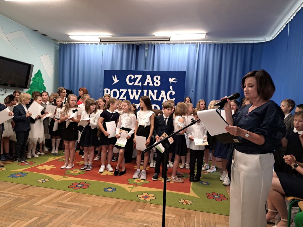Klasy trzecie oczekują na kolejny punkt uroczystości zakończenia roku szkolnego zapowiadany przez konferansjera