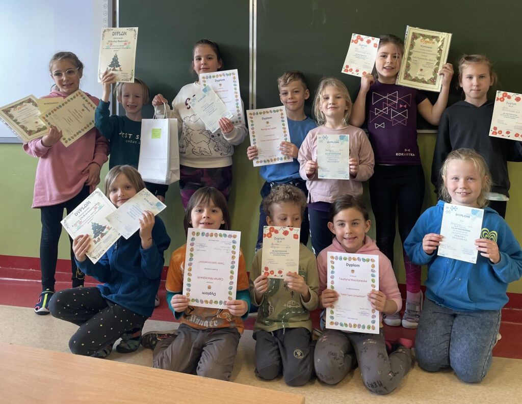 Uśmiechnięci uczniowie z klasy IB prezentują swoje dyplomy zdobyte za udział w różnych konkursach