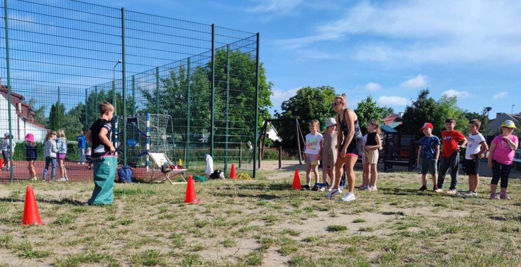 Dzieci oczekujące na kolejną konkurencję sportową na placu przy szkole