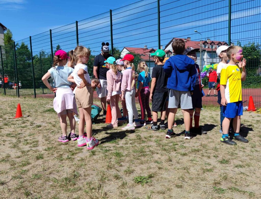 Grupa dzieci oczekująca na wykonanie zadania sportowego.